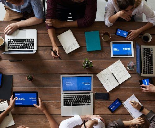 A birds eye view of a group of people working on laptops around a table.