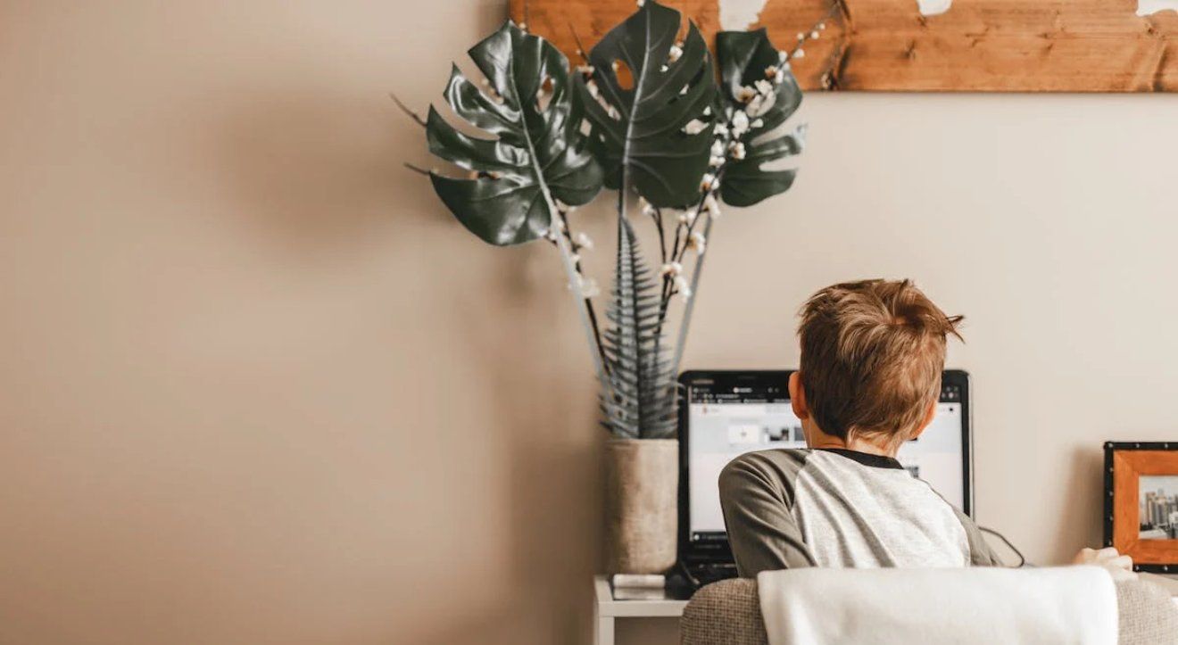 A child working at a computer, seen from behind.